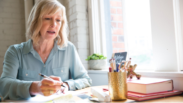 Woman sitting at desk and writing in a notebook