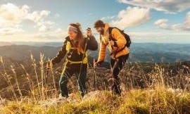 Two hikers climbing a grassy mountain ridge at sunrise