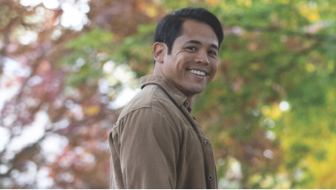 Image of smiling man with blurred trees in the background.