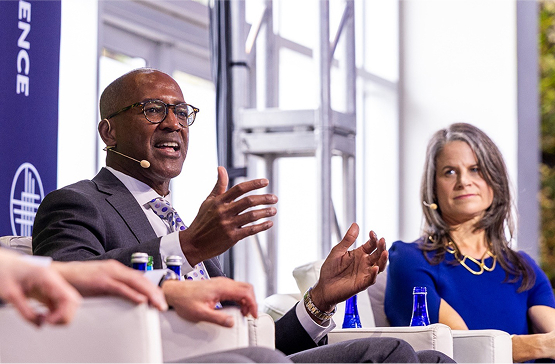 Nationwide's Eric Stevenson on a stage at the Milken Conference, speaking to the audience.