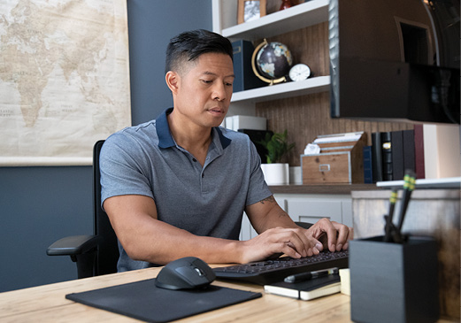 hombre sentado en un escritorio que escribe en un teclado